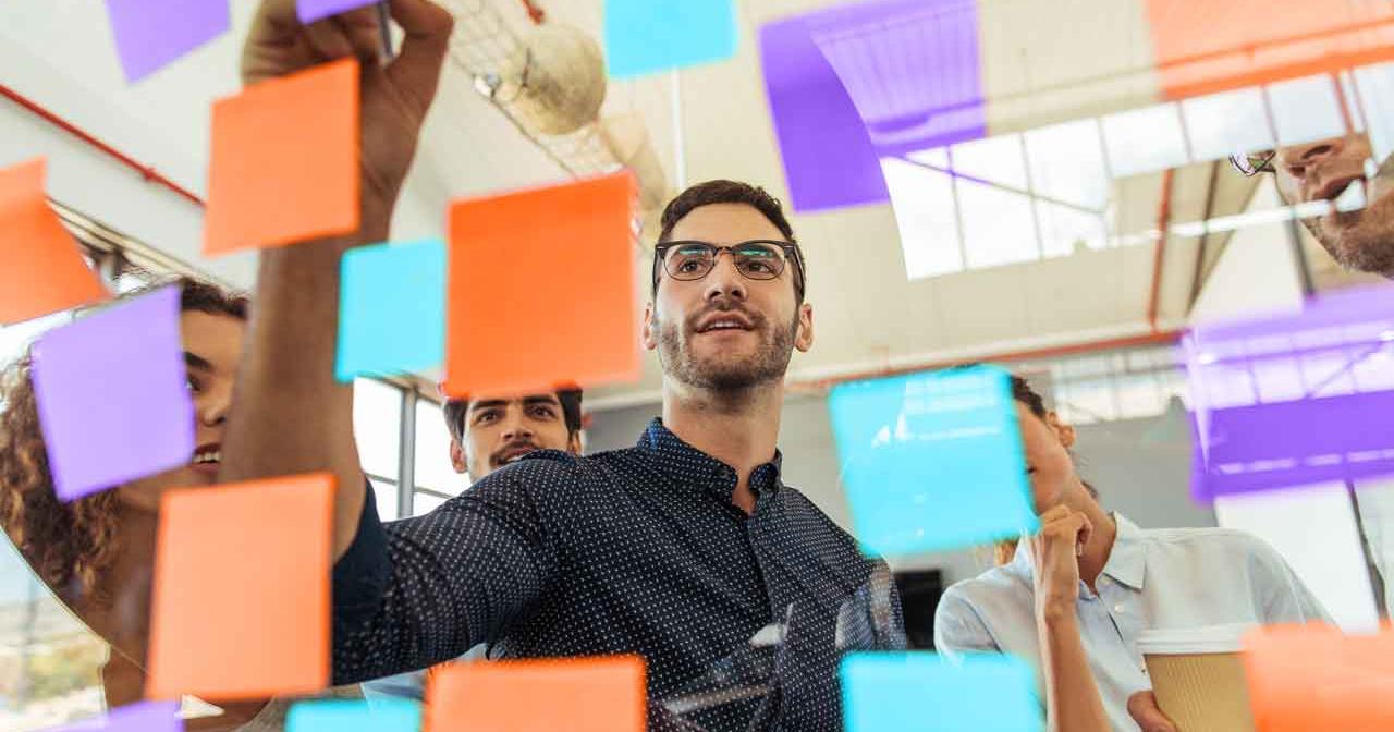 man-writing-on-colorful-sticky-notes